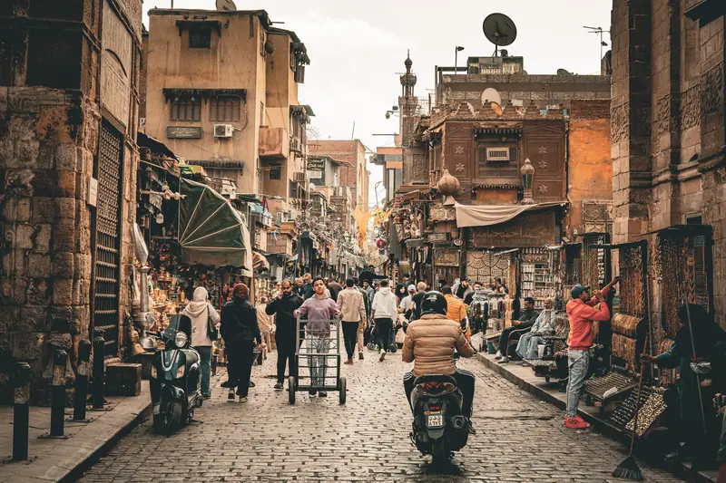 Die Al-Muizz-Straße in der Altstadt von Kairo mit Läden, Mopeds und Fußgängern