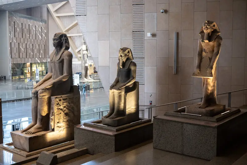 Drei beleuchtete Pharaonenstatuen in der hohen Halle des Museums