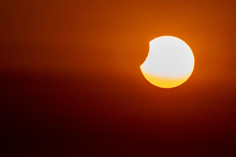 Die teilweise verdeckte Sonne geht orangerot unter