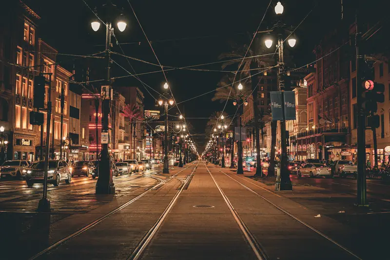 Die Canal Street in New Orleans bei Nacht mit Straßenbahnschienen und Laternen