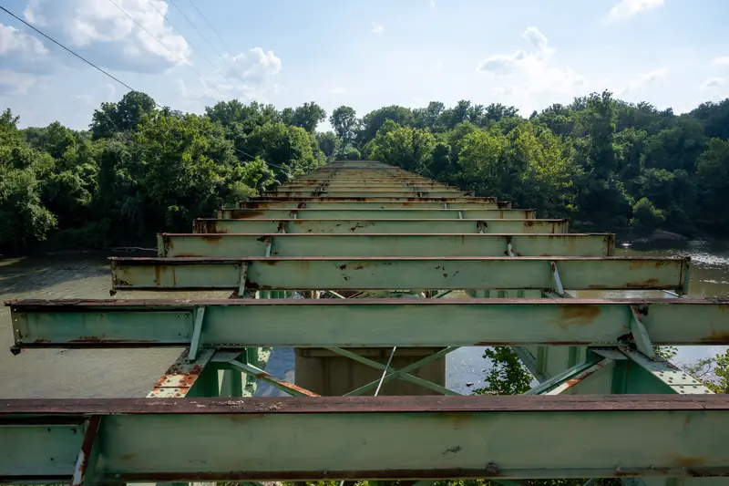 Verrostete Gleisträger einer alten Eisenbahnbrücke über einem Fluss