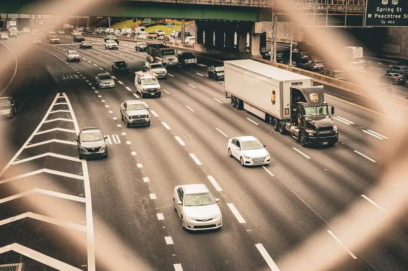 Vielspuriger Highway in Atlanta mit Lastwagen, durch einen Zaun fotografiert