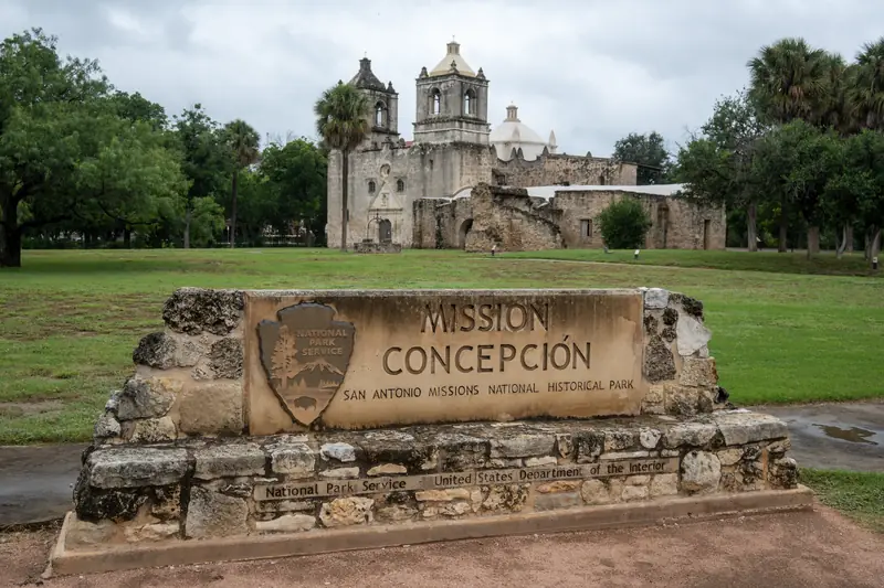 Die Mission Concepción in San Antonio hinter einem steinernen Schild